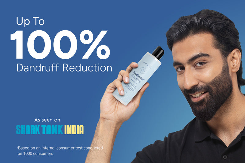 Man holding a bottle with dandruff reduction claim on a blue background