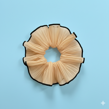 Beige scrunchie with black edges on a light blue background