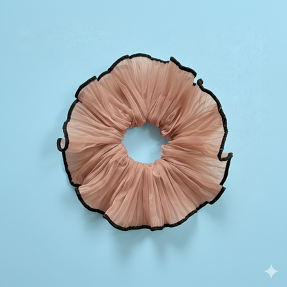 Pink pleated scrunchie with black edges on a light blue background