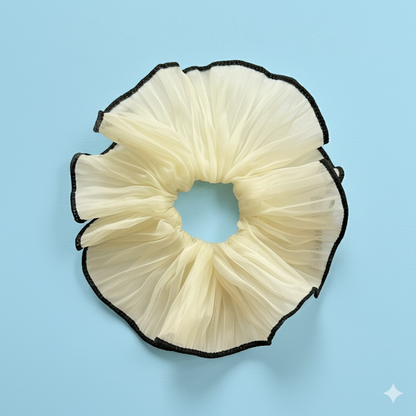Cream-colored scrunchie with black edge on a light blue background