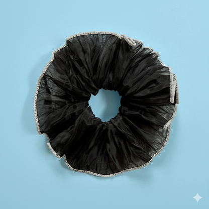 Black scrunchie with lace trim on a light blue background